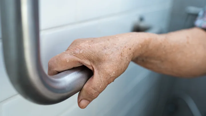 Senior holding safety bar in bathroom